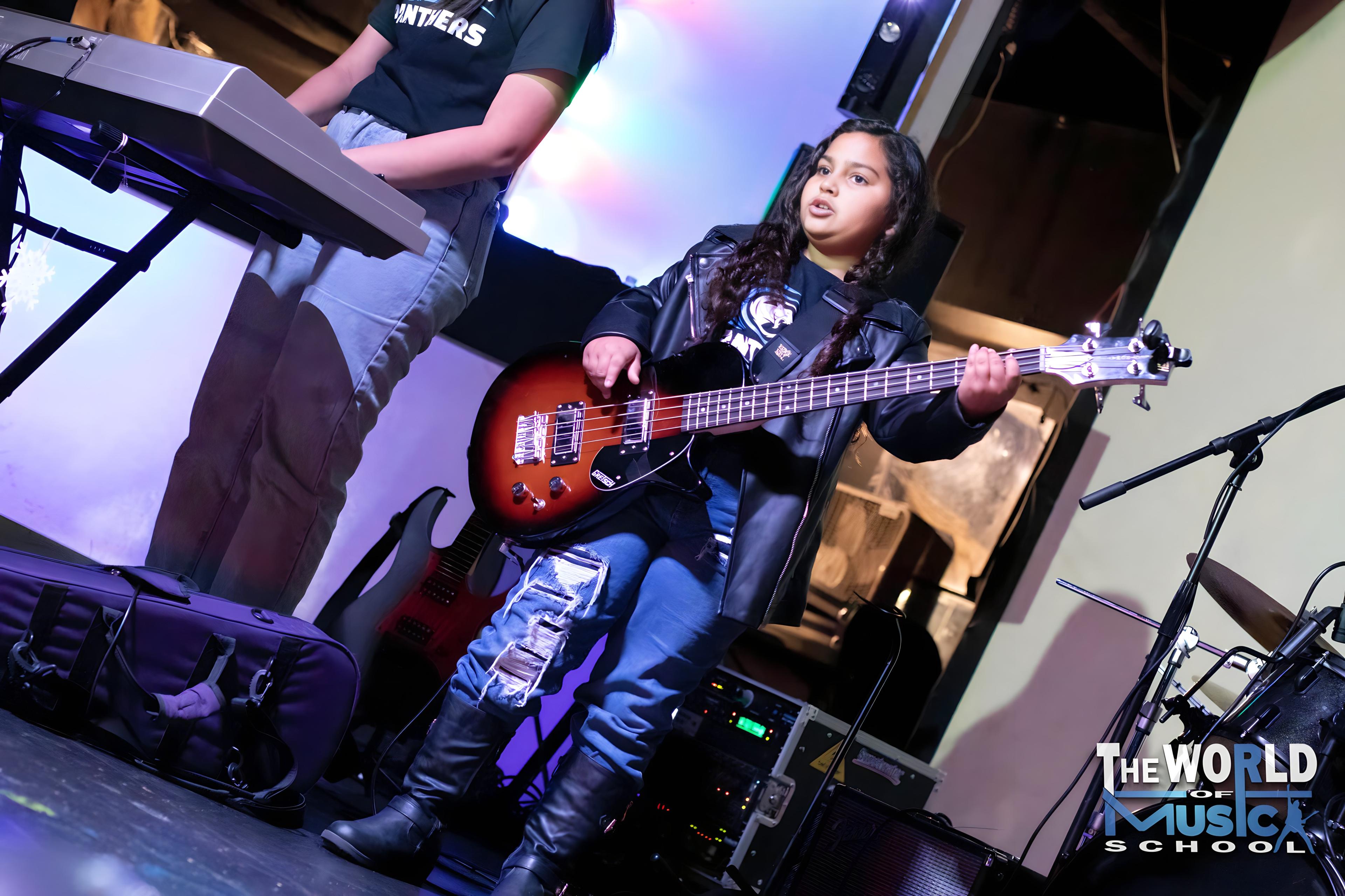 Young girl playing bass guitar on stage at band concert