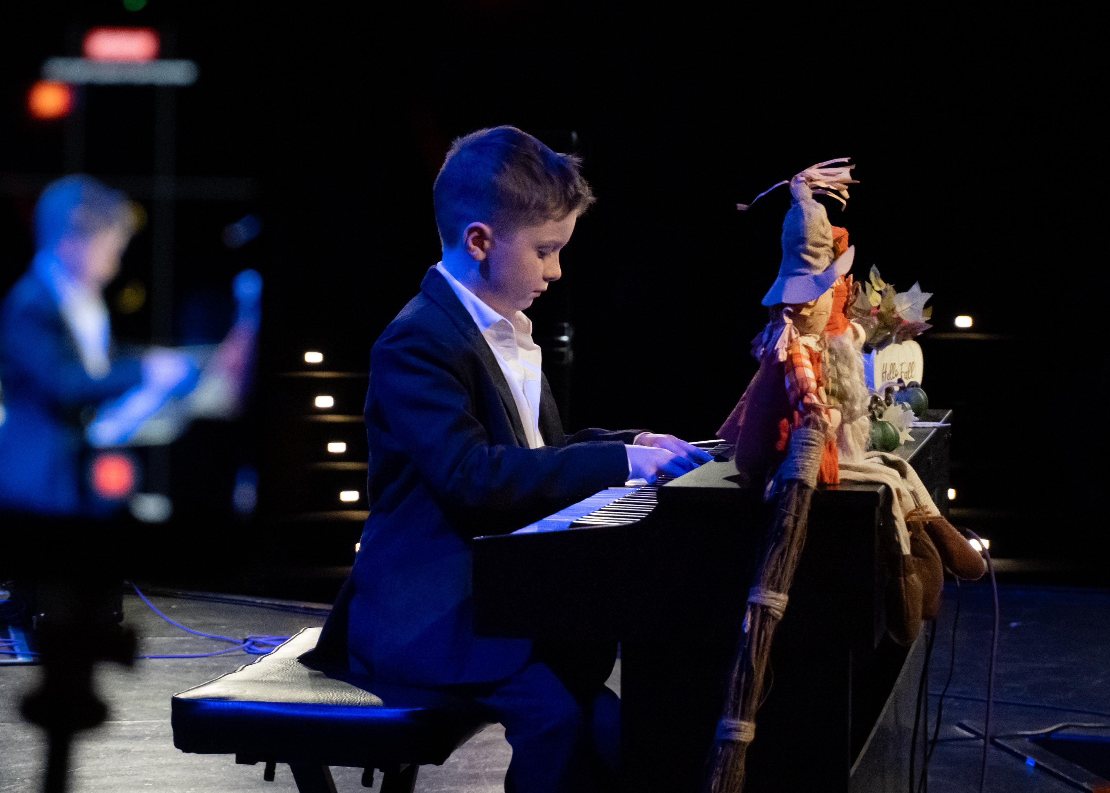 Student pianist performing on a darkened stage