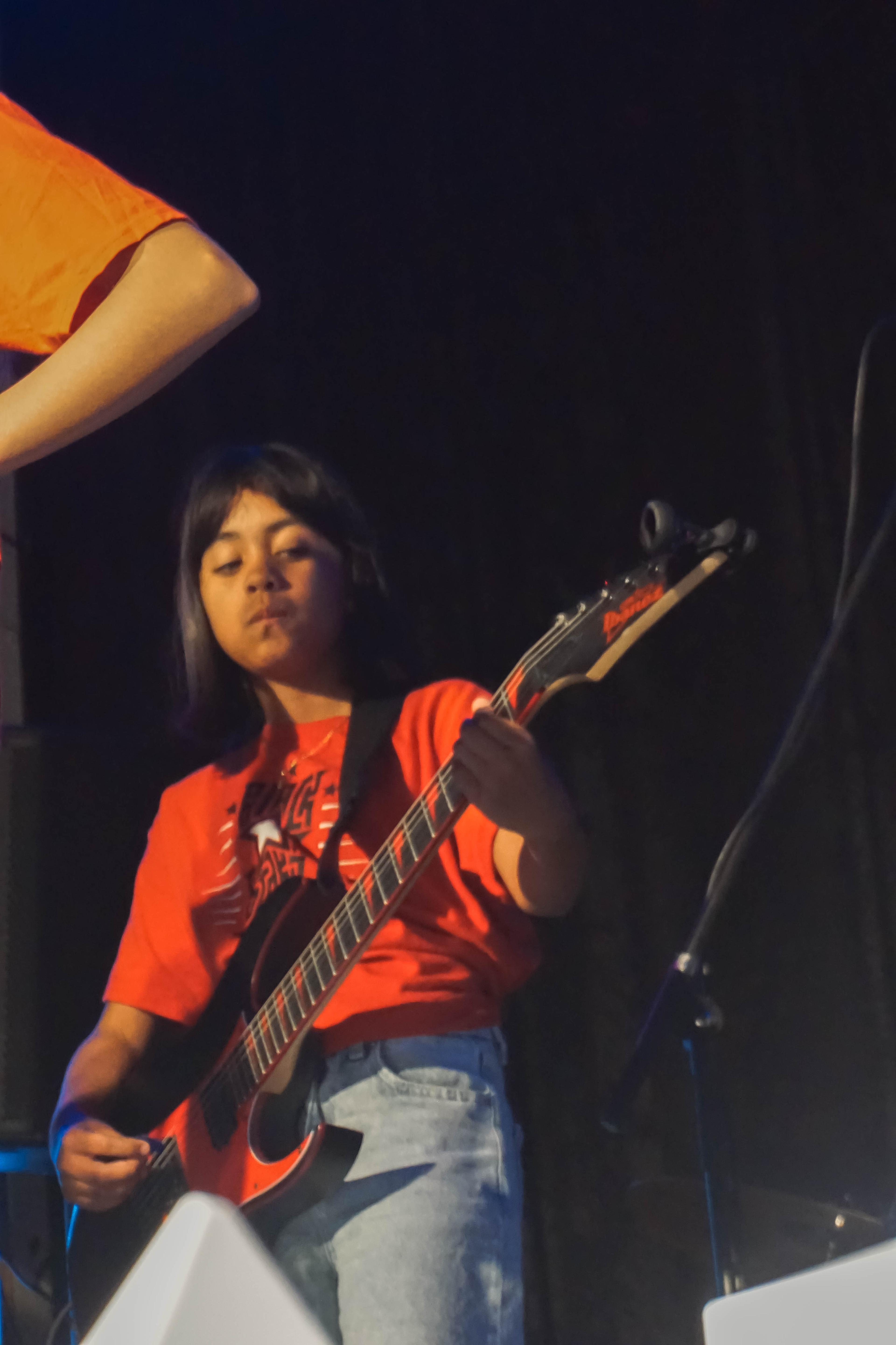 Girl playing guitar on stage at concert