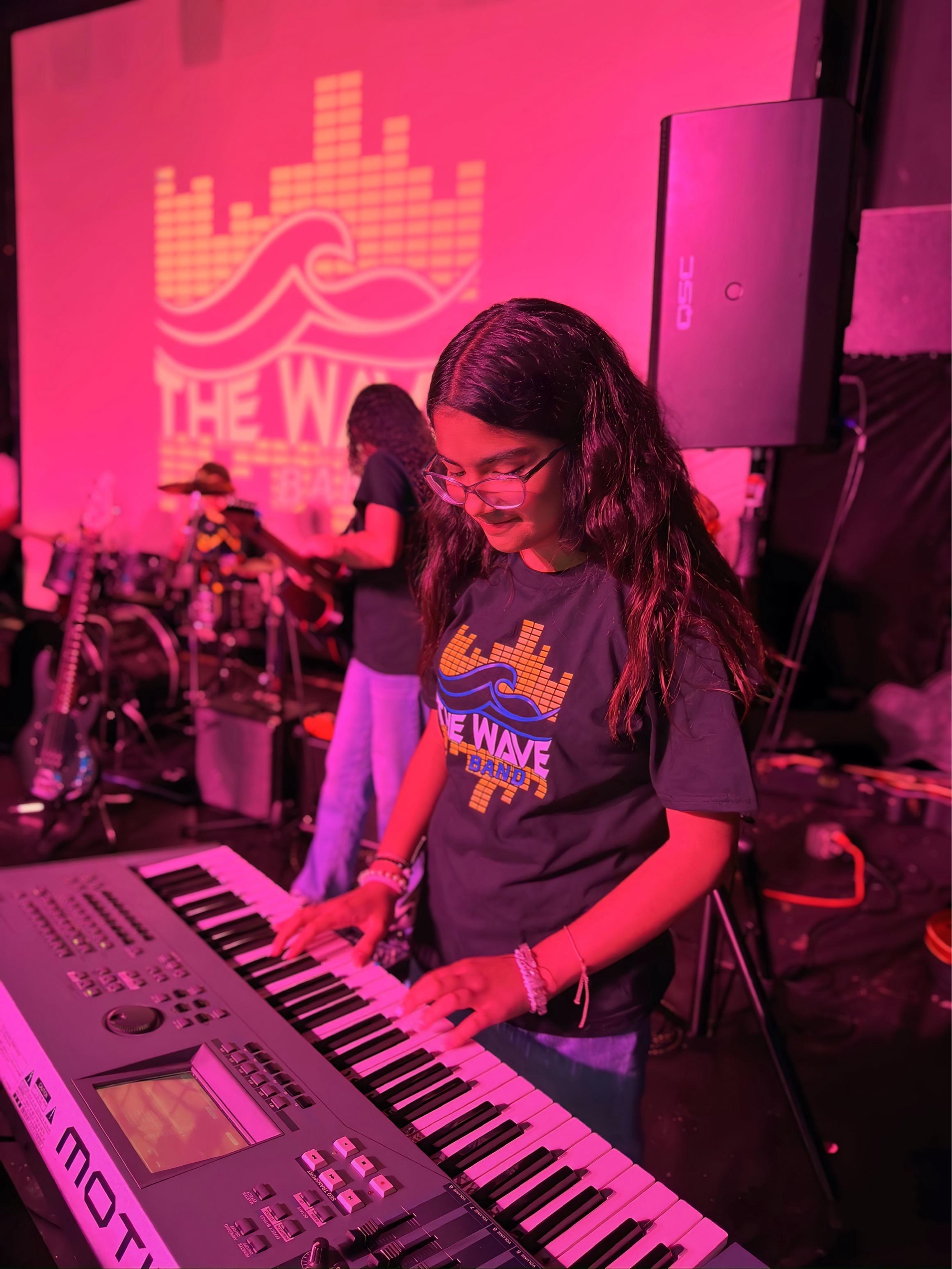 Keyboardist performing under pink lights
