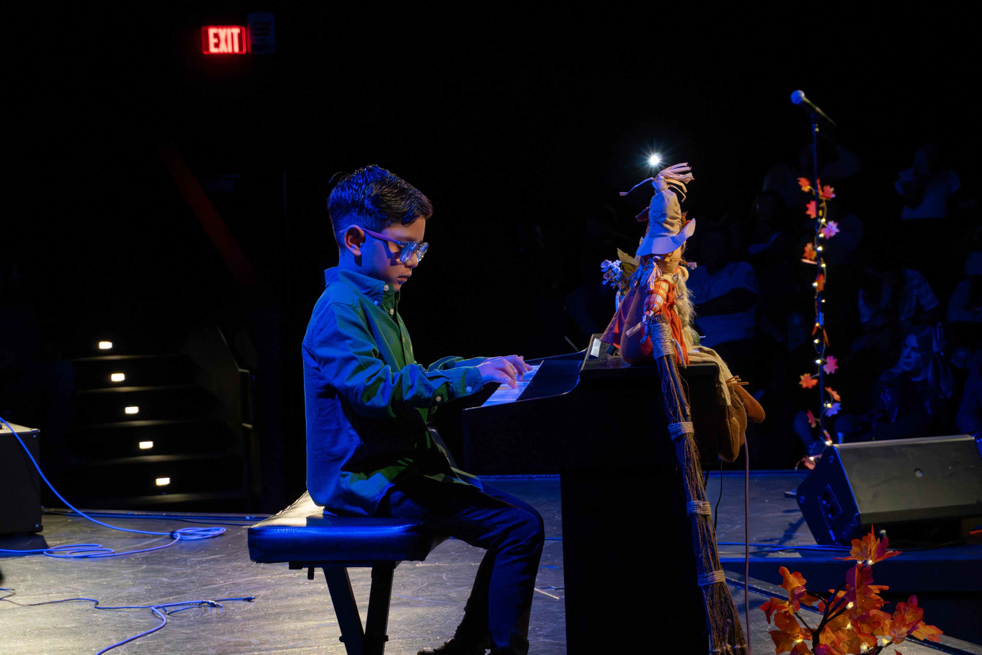 Boy in blazer performing piano solo at Clermont PAC