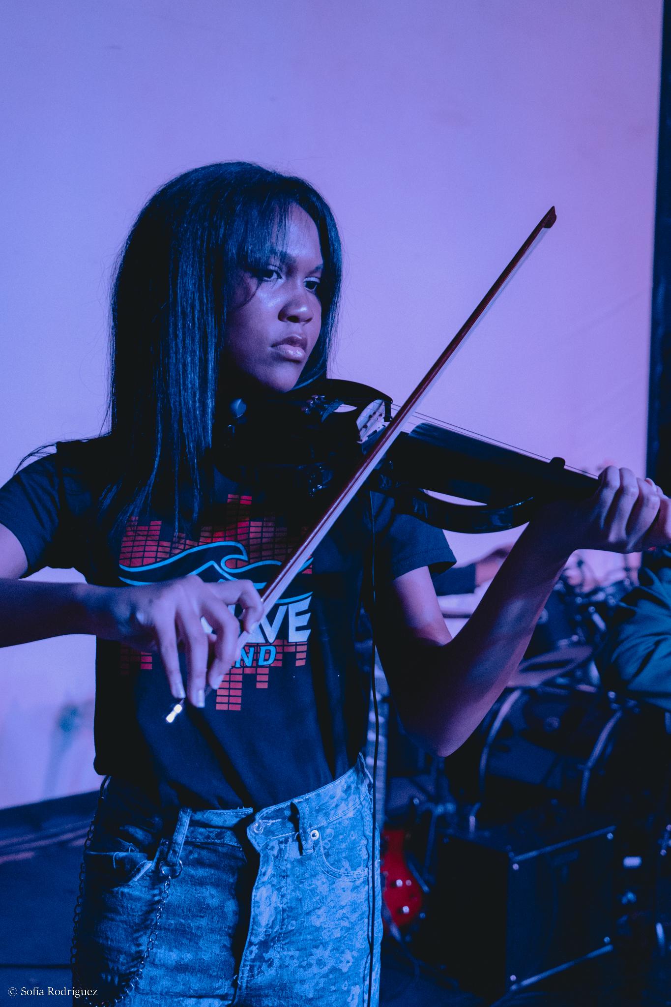 Violin student performing on stage with band